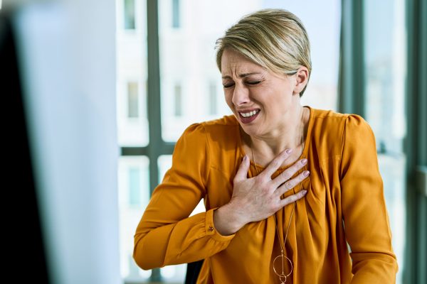 Young distraught businesswoman feeling chest pain while working in the office.